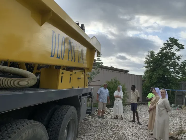 Sisters and workers standing around a construction truck