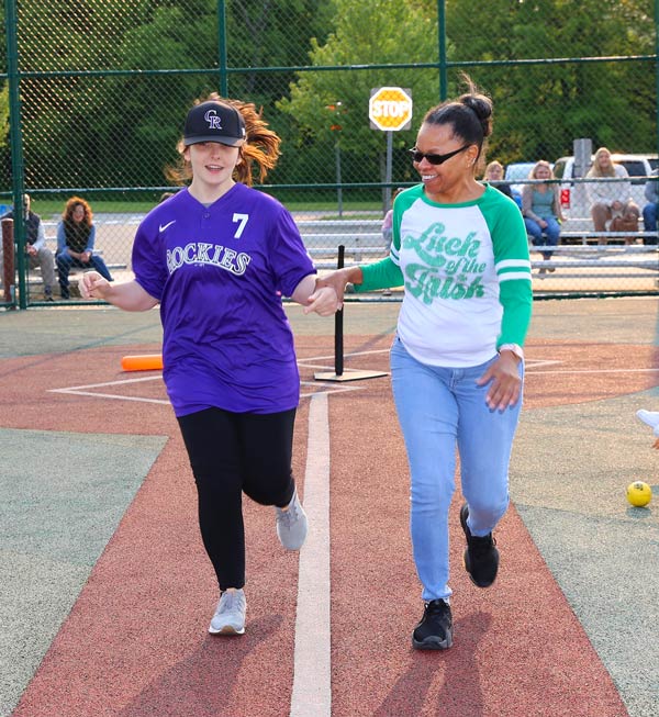 Teenage girl and woman aide run on a track.