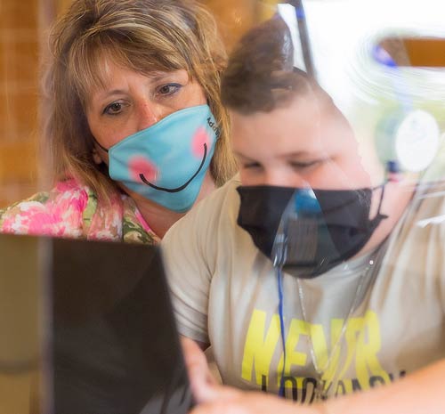 Boy student with woman teacher working on a computer.